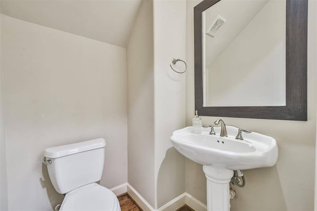 Sleek and functional powderroom with a classic pedestalsink, brushed nickel fixtures, anda large framed mirror—perfectfor guests