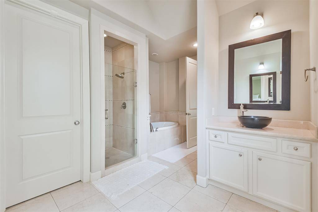 A full view of the primary bathshows the walk-in shower,soaking tub, and sleek vanitysetup, all tied together withpolished tile flooring.