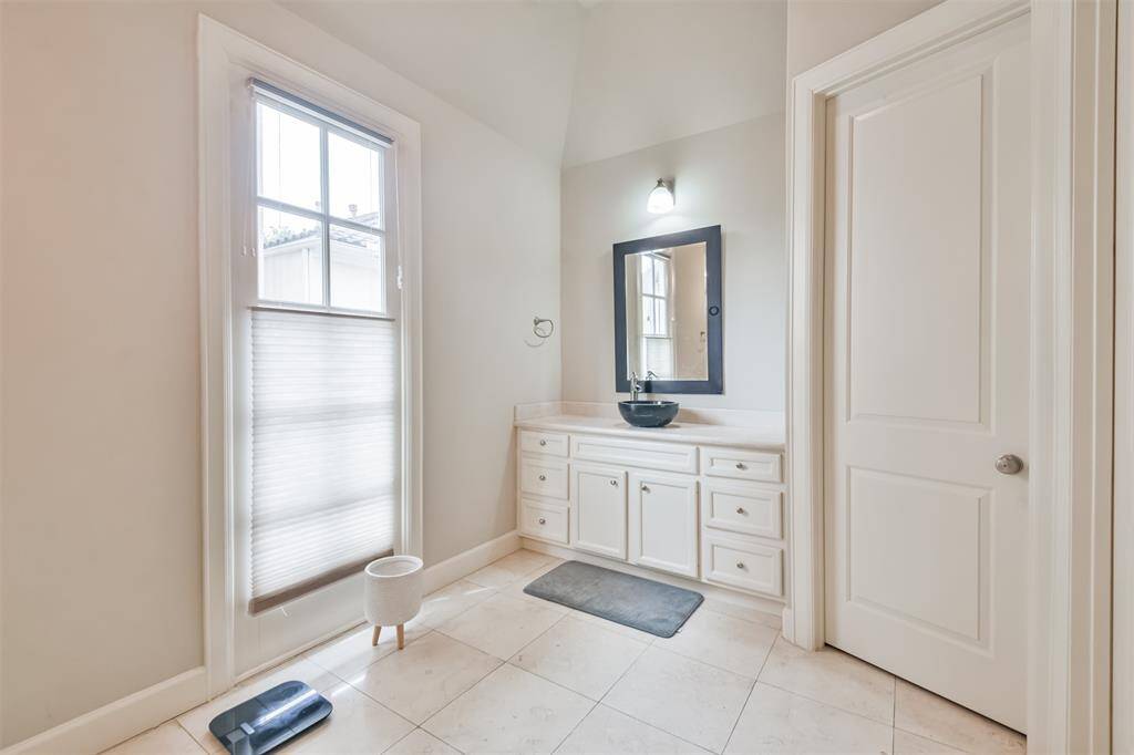 The primary bathroom features amodern vessel sink, framedmirror, and generous cabinetstorage under soft naturallighting. Enjoy access to theprivate balcony via the frenchdoor.
