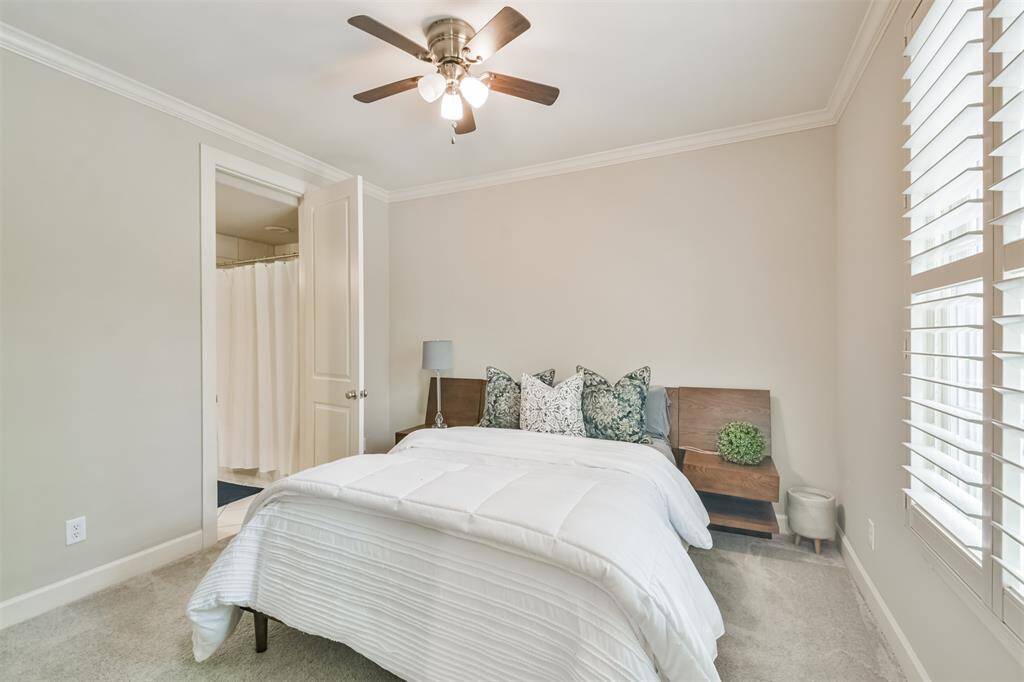 This secondary bedroomfeatures custom windowshutters, crown molding, andensuite bath access—offeringprivacy and comfort for visitors.