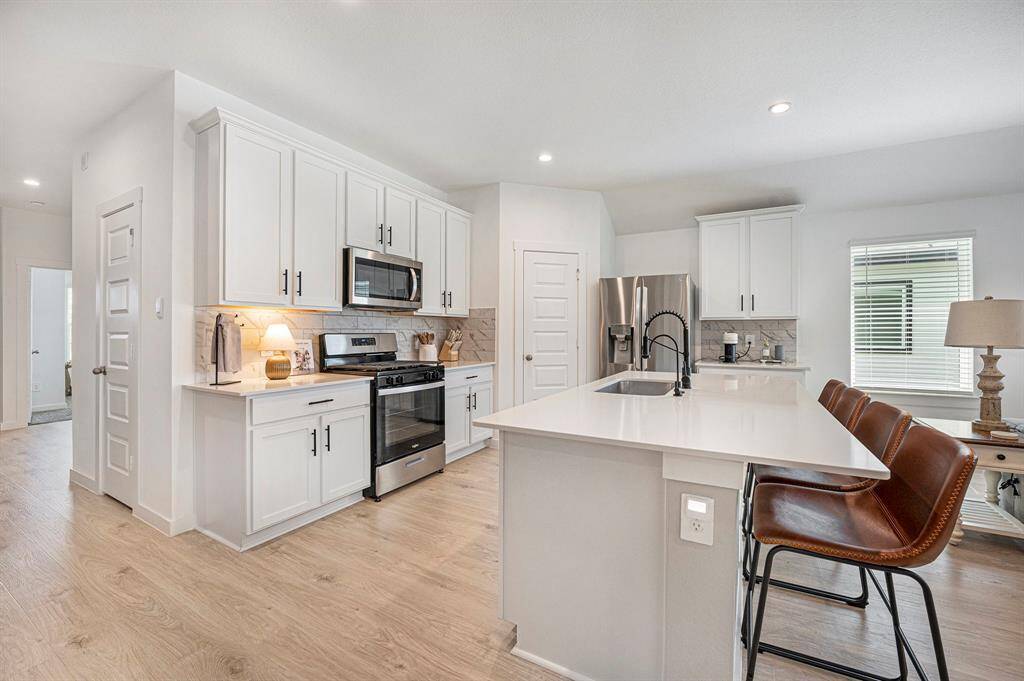 Bright and modern kitchen featuring ample cabinet space and sleek stainless steel appliances—designed for both style and everyday functionality.