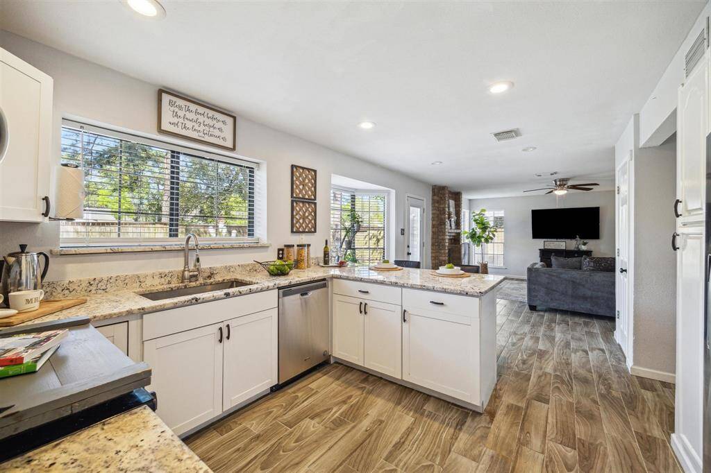 Bright, open sun lit kitchen with stainless steel appliances, seamlessly connecting to the family room.
