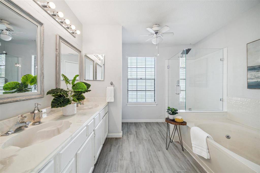 Luxurious ensuite featuring dual sinks, a soaking tub, walk-in shower, and spacious closet.