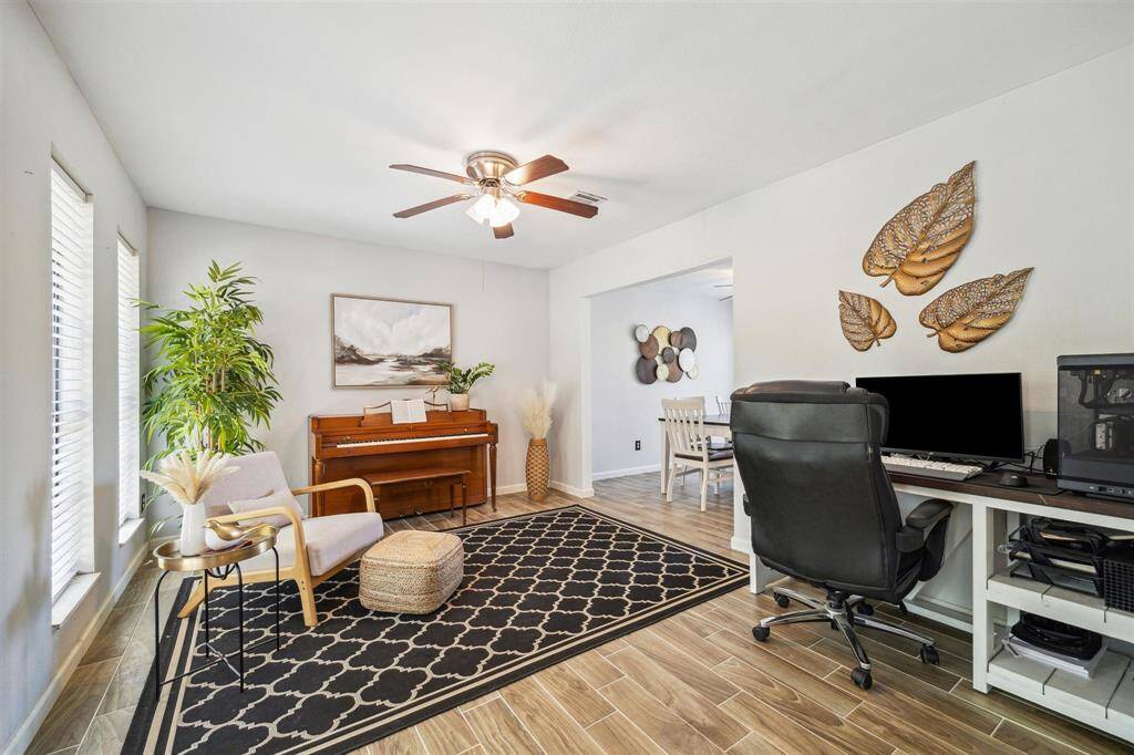 This inviting formal living room features natural light from large windows that highlight the wood-look flooring.