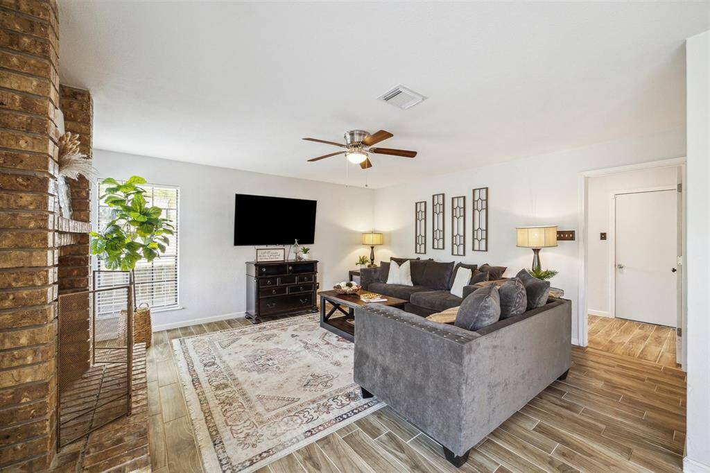Cozy family room with a charming brick fireplace, ideal for relaxation and entertaining as it is open to the kitchen.