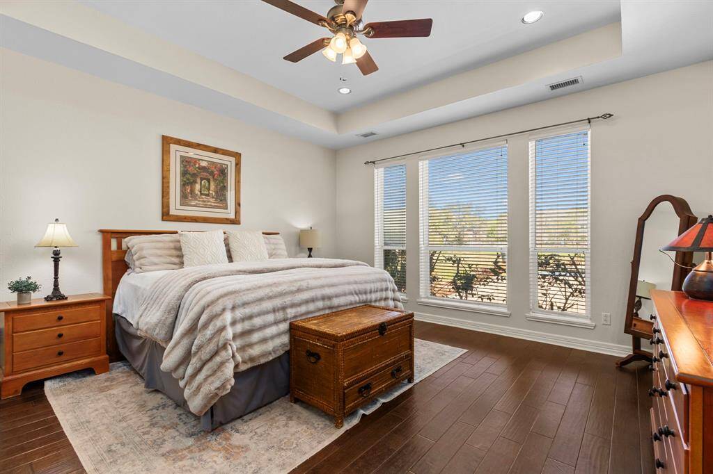 The Primary Suite is located on the first floor, featuring beautiful wood floors, a sophisticated pop-up ceiling, and three large windows that offer serene views of the backyard.