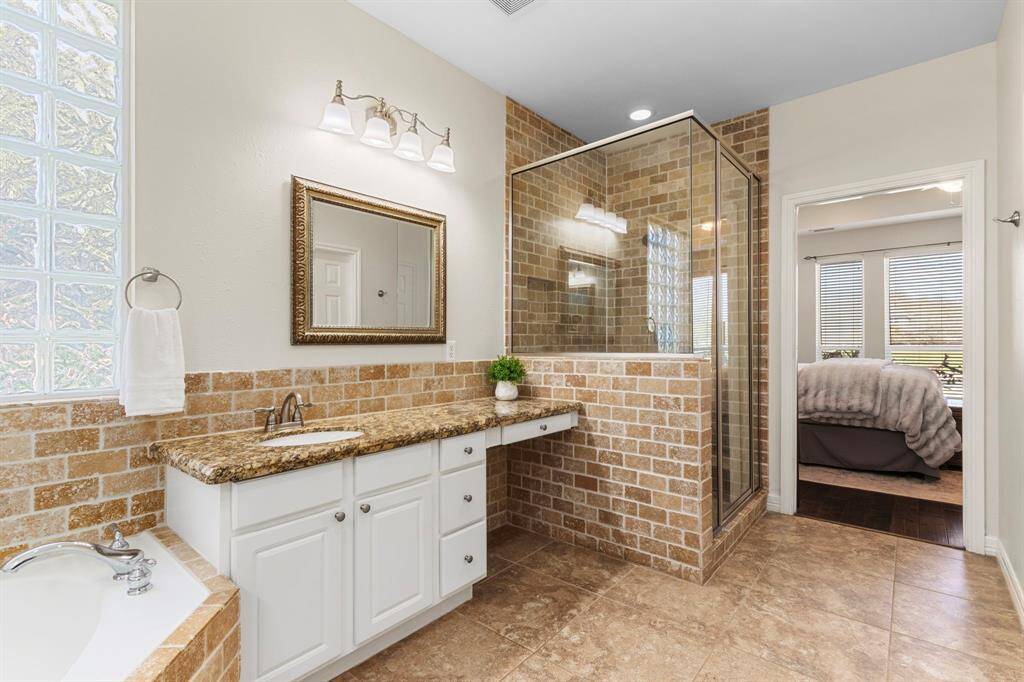 The Primary Bath showcases undermount sinks with brushed nickel faucets and lights fixtures, complemented by a large walk-in shower featuring a shower wand and elegant 2x4 brick pattern travertine tile for a spa-like experience. There is also a large walk-in closet and linen closet.