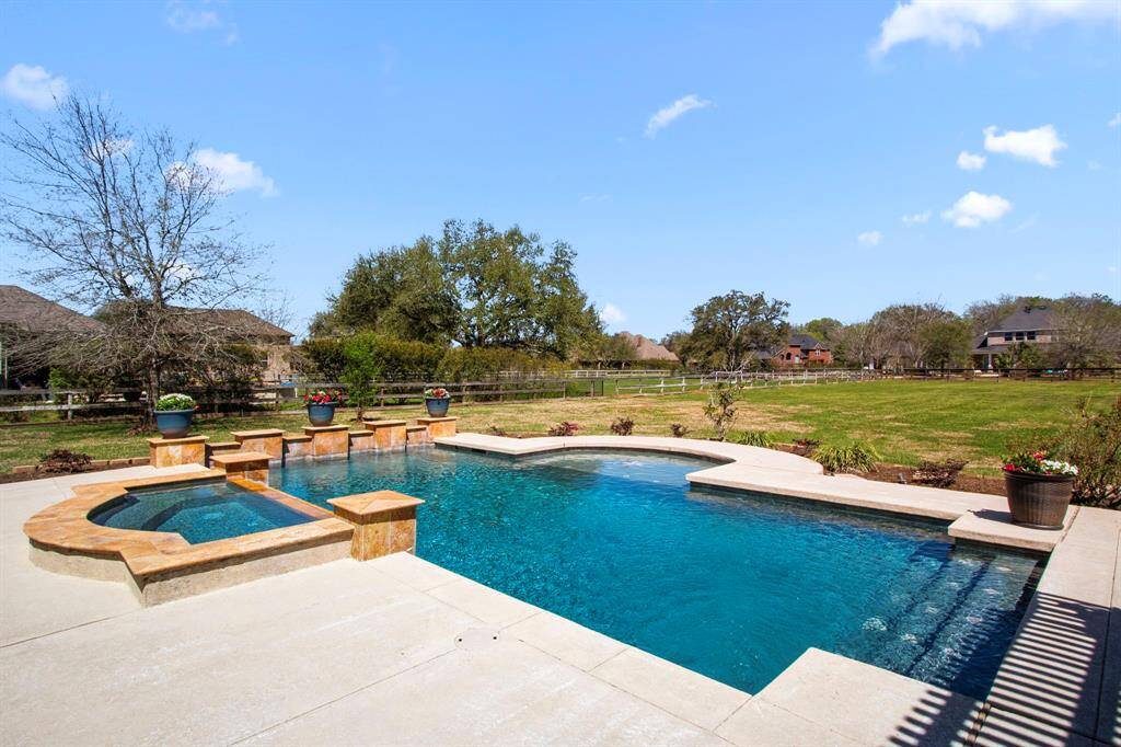 The pool is beautifully landscaped along the back and side, featuring built-in ledges perfect for displaying potted plants, adding a touch of greenery and charm to the space.