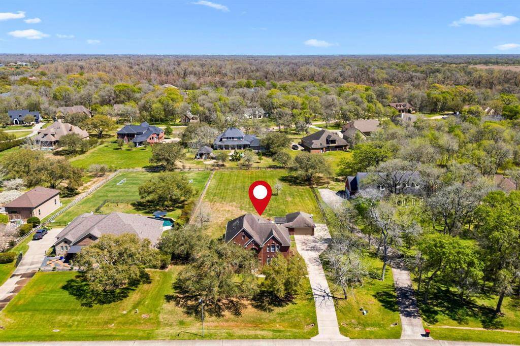 This view looks east and highlights the surrounding area of the property. This section of Weston Lakes is known for its acre-plus lots, providing spacious living, privacy, and a serene setting. The backyard faces east, offering ample shade under the covered patio—perfect for relaxing or entertaining.