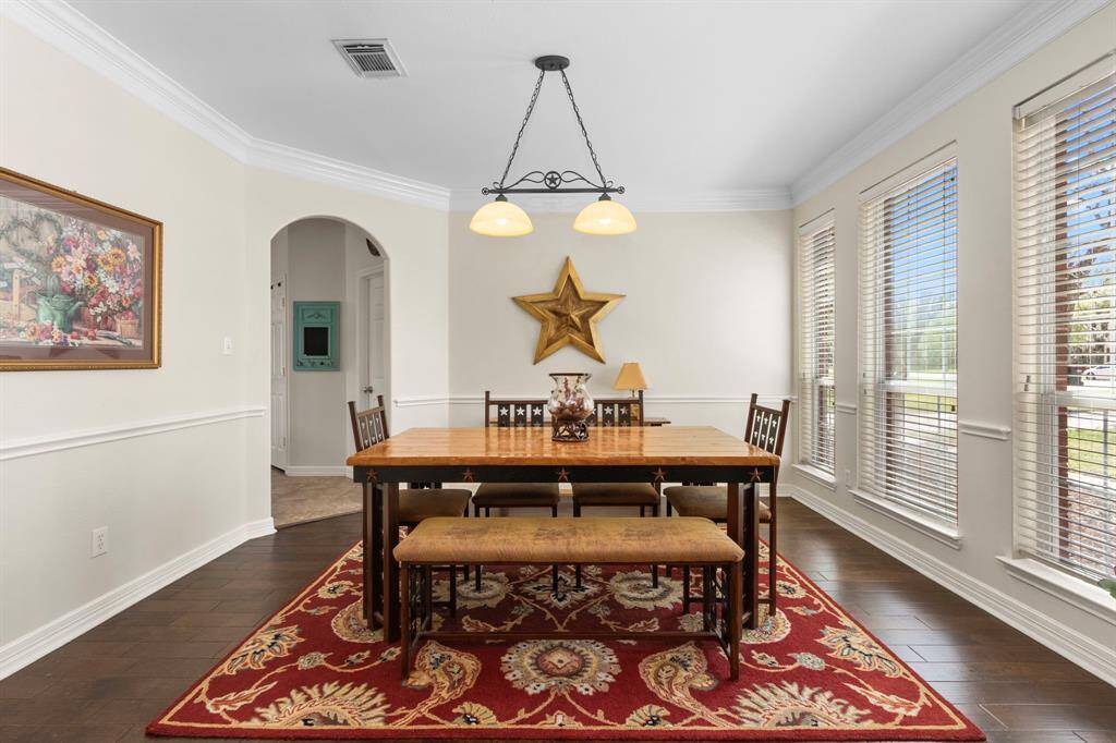 The Formal Dining Room is gorgeous, featuring elegant crown molding, chair rails, and 3 large windows with blinds that fill the space with natural light. Through the doorway in the distance, you'll find easy access to the Kitchen, making entertaining effortless.