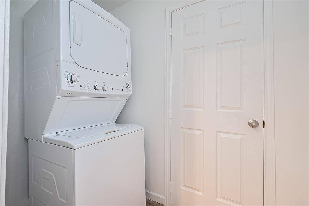 Compact laundry nook featuring a stacked washer and dryer unit beside a white paneled door, ideal for maximizing space.