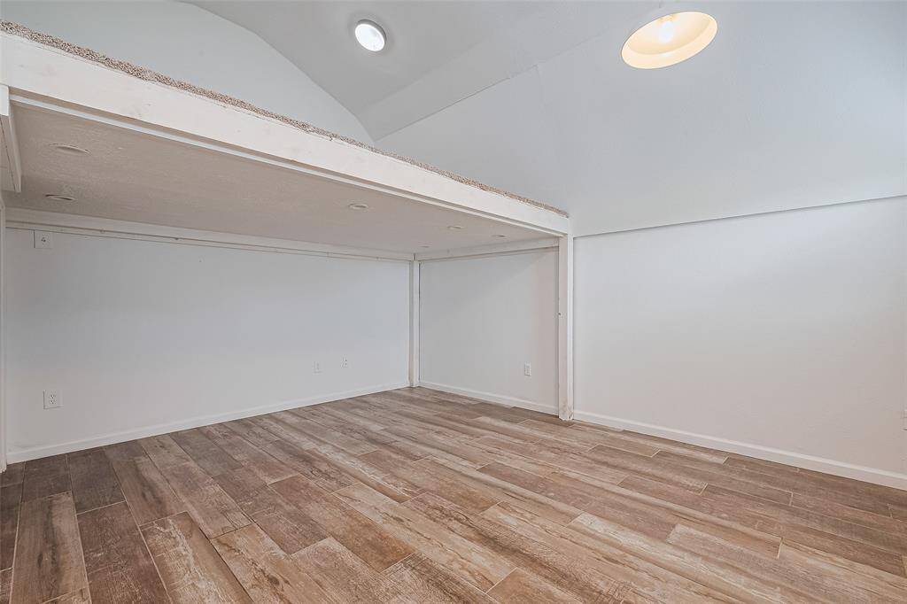 Versatile upstairs flex space with vaulted ceilings and wood-look tile flooring, perfect for a home office, media room, or creative retreat.