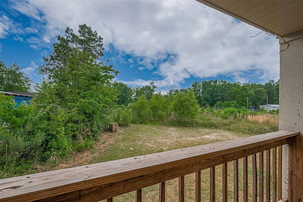 Scenic view from the back porch overlooking a spacious, partially cleared yard surrounded by lush greenery and mature trees—perfect for privacy and outdoor enjoyment.