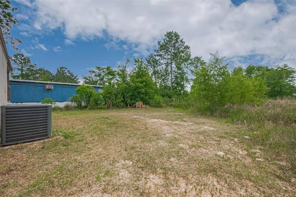 Spacious backyard with open, level ground surrounded by mature trees and natural brush—ideal for adding a garden, workshop, or recreational space.