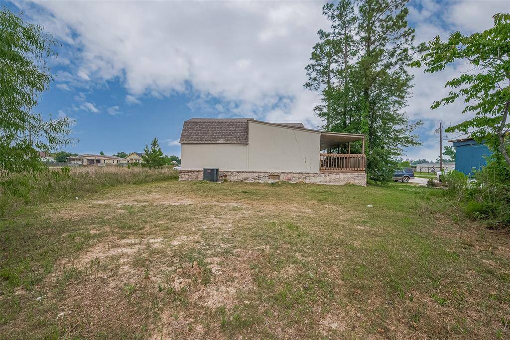 Backyard view of the home showcasing the spacious lot, central HVAC unit, and large wraparound porch—ideal for entertaining, outdoor play, or future expansion.