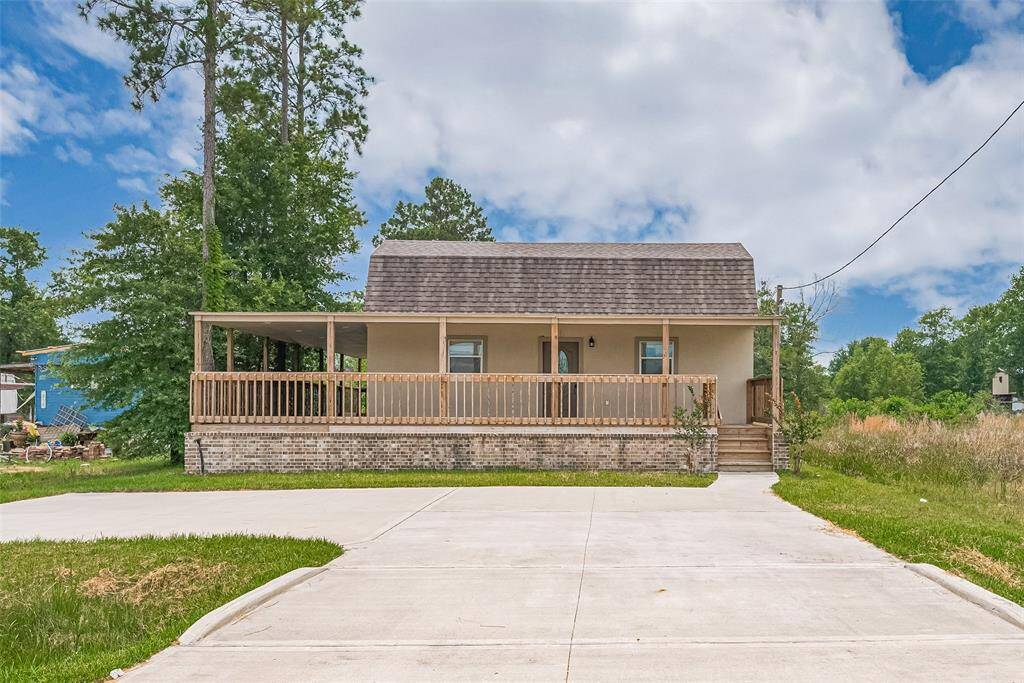Charming two-story home with a large wraparound front porch, elevated entry, and wide concrete driveway. Surrounded by mature trees and open green space, it offers a peaceful setting with classic curb appeal.