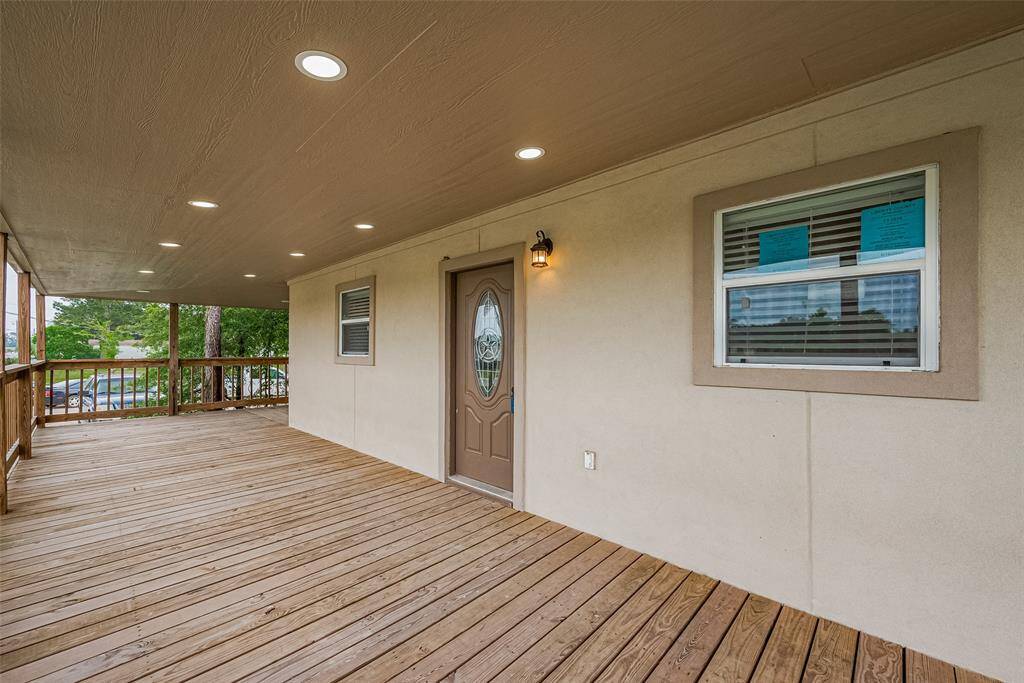 Spacious covered front porch with wood decking, recessed lighting, and a welcoming entry door—perfect for relaxing outdoors in any weather.