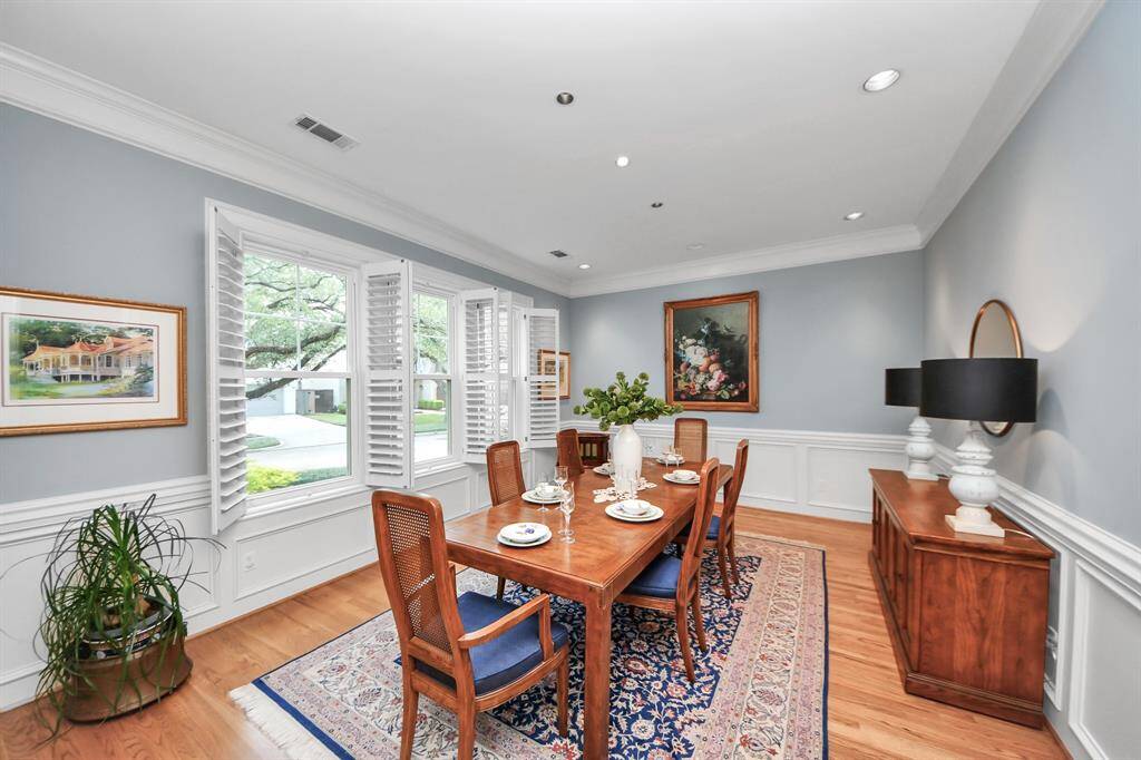 An inviting, oversized dining room with abundant natural light, custom millwork, crown molding, and chair rail for added architectural charm.