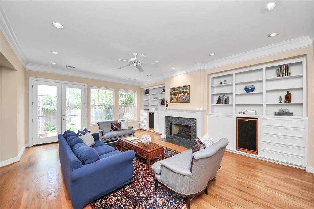 Spacious living area featuring built-ins, a cozy fireplace, and a wall of windows with direct access to the charming patio.