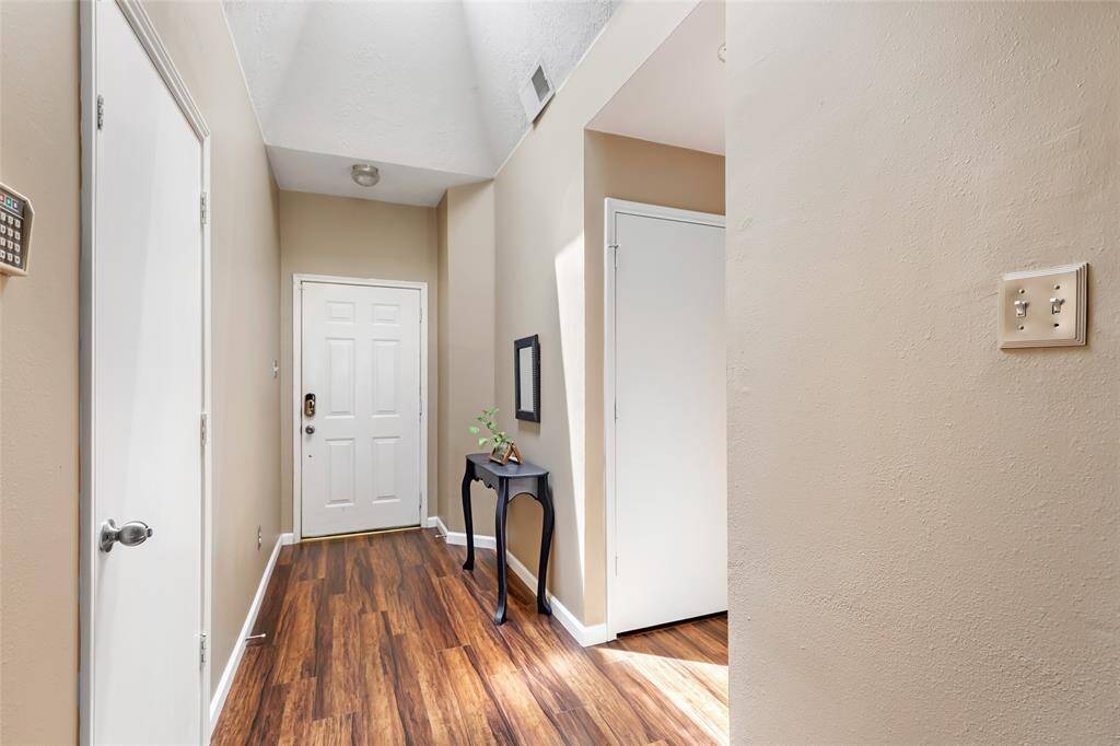 A view of the front door. The door on the left leads to the garage.  Hallway to the right in this picture leads to the laundry room, a secondary or guest bath and two secondary bedrooms.