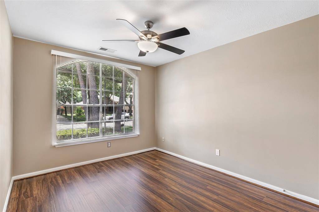 This is one of the secondary bedrooms and features neutral walls, laminate wood flooring, and a ceiling fan. A large window with blinds overlooking the front yard that offers plenty of natural light.