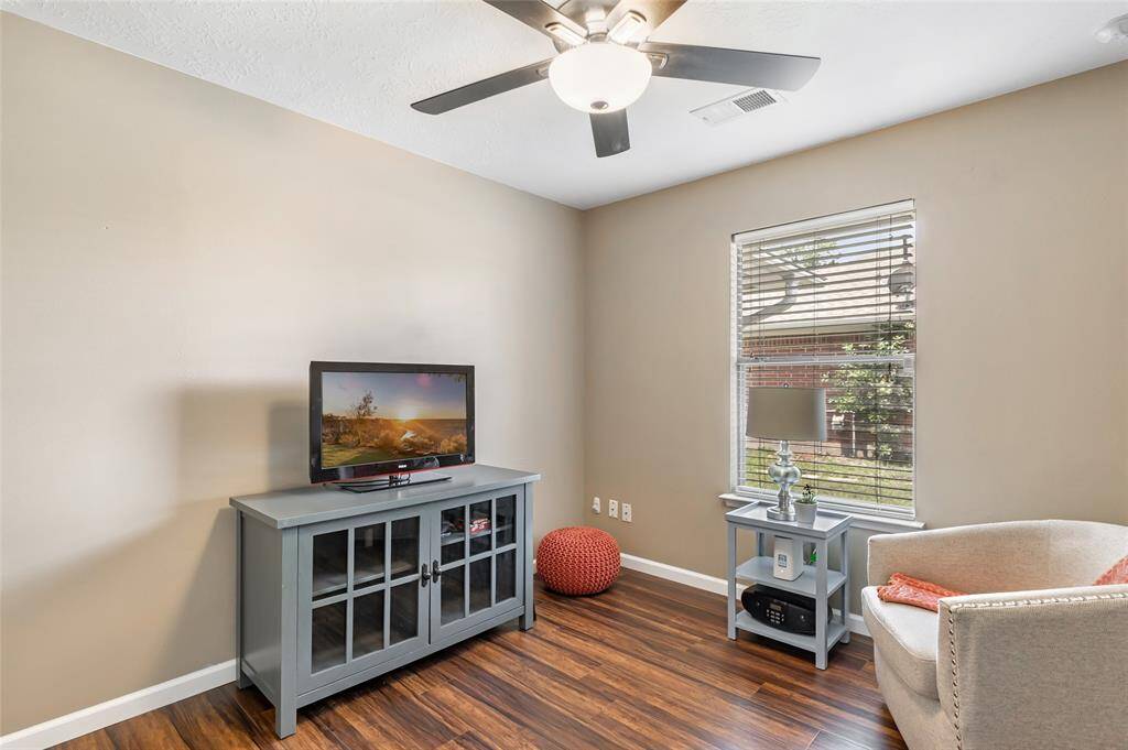 This room is currently set up as an office with laminate wood flooring and a ceiling fan. The window provides natural light, enhancing the warm, neutral wall tones. This room is ideal for a 4th bedroom (small closet not pictured), or a small entertainment or reading area.