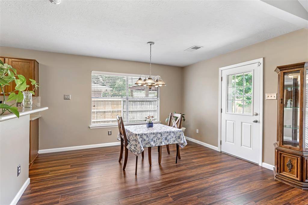 This bright breakfast area is perfect to start your morning! It features laminate wood flooring, a large window, and a glass-paned door, allowing plenty of natural light. It is adjacent to the kitchen, offering a welcoming space for meals and gatherings.