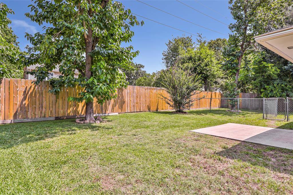 Spacious backyard with a wooden privacy fence. Includes a small concrete patio area and a gated section, perfect for outdoor activities and relaxation.