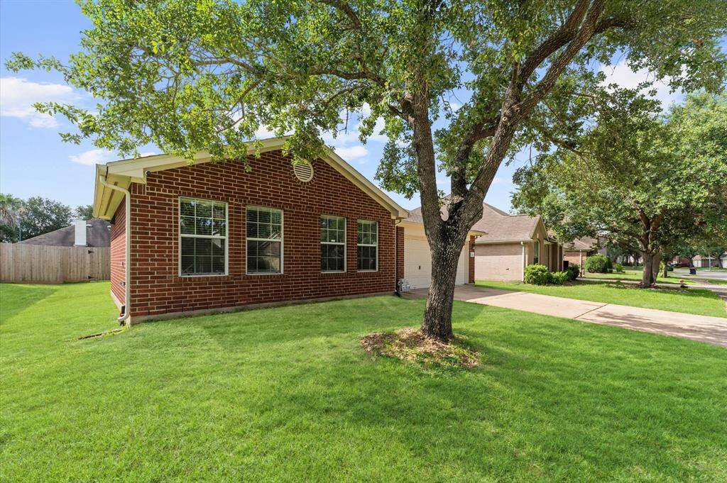 Charming brick home with large windows, a well-maintained lawn, and a mature tree offering shade. Situated in a quiet neighborhood, it features a paved driveway and a spacious front yard.