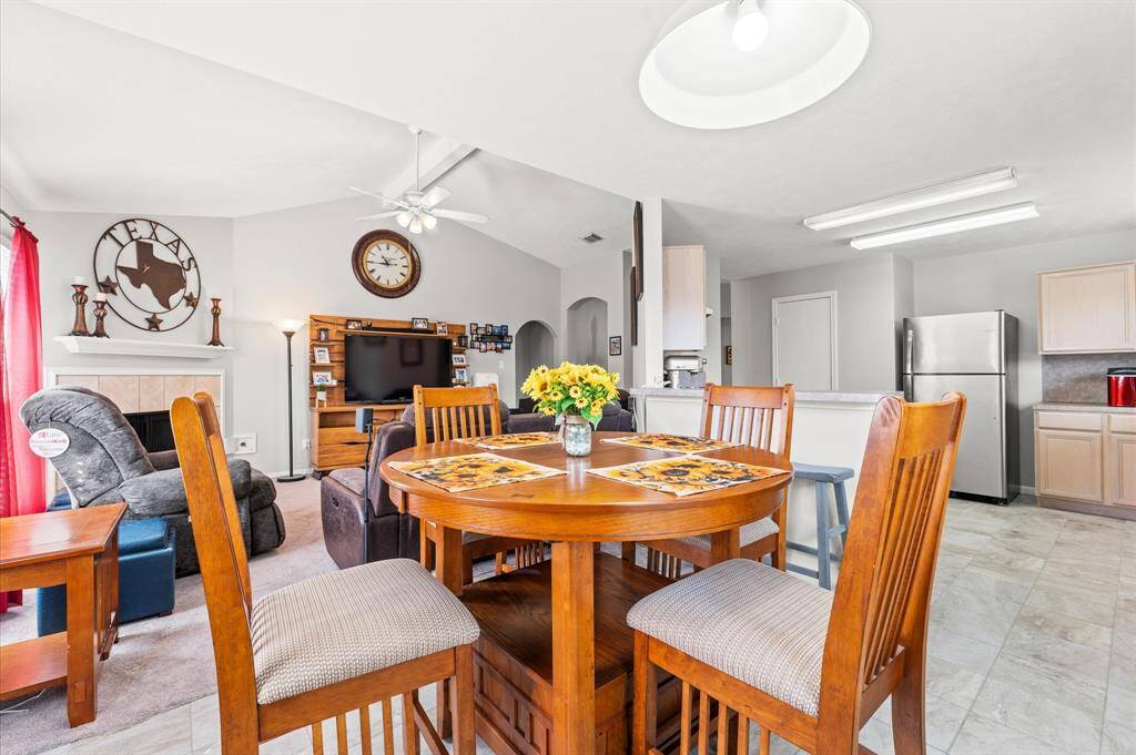 This photo showcases a bright, open-concept living area with a cozy atmosphere. It features a dining area, a comfortable living room with a fireplace, and a modern kitchen with stainless steel appliances. The space is well-lit and inviting, ideal for family gatherings.