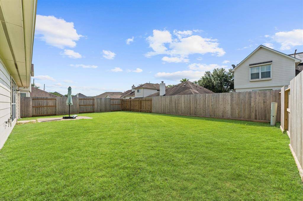 Spacious backyard with well-maintained lawn, bordered by a wooden privacy fence. Ideal for outdoor activities and relaxation.