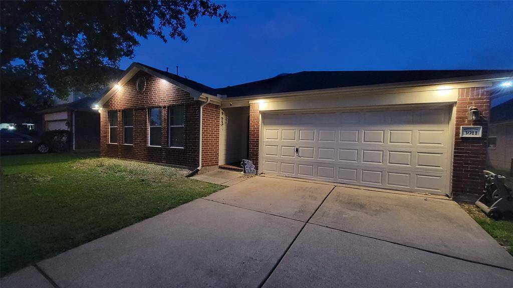 Photos taken at night to showcase the under eave lighting.  Charming single-story brick home with a two-car garage, well-lit exterior, and a neat front lawn. Perfect for comfortable living in a quiet neighborhood.