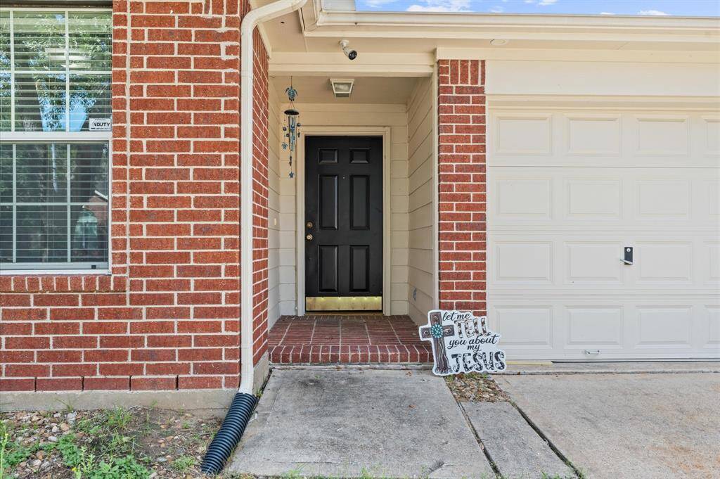 This home features a welcoming front entry with a classic black door, sheltered by a small porch area. It's complemented by a red brick exterior and adjacent garage, offering a neat and inviting appearance.