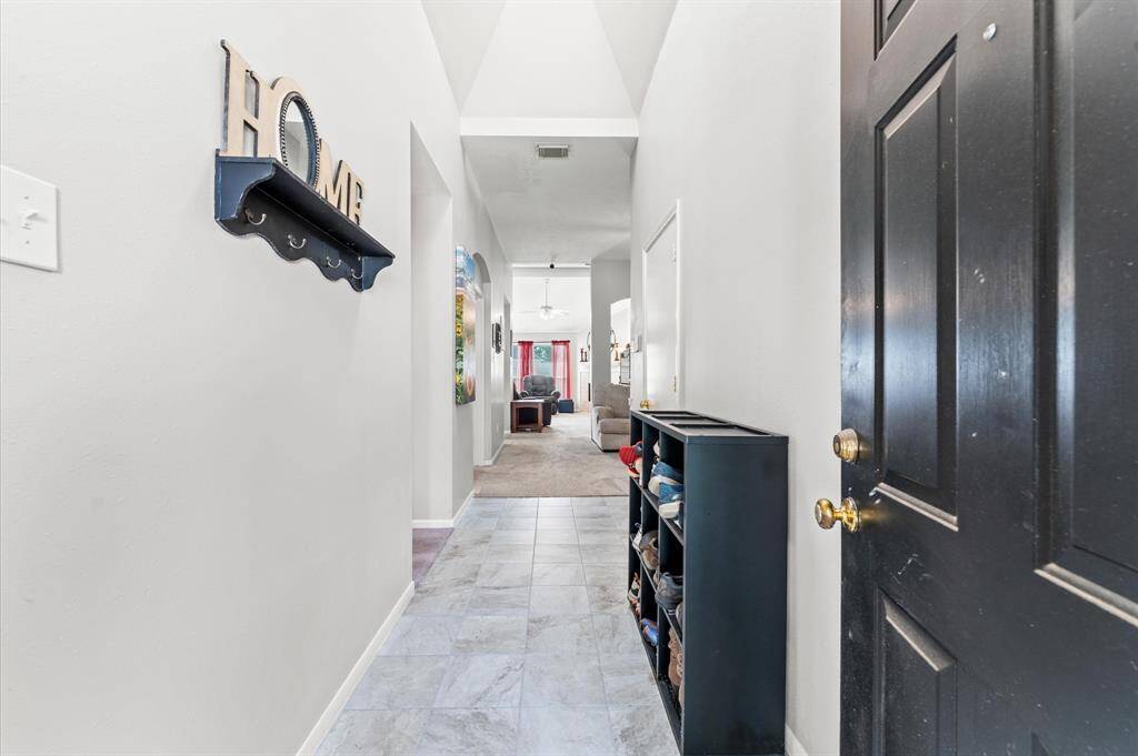 Welcome to a bright, inviting entryway with tiled flooring and ample natural light. The hallway leads to an open living area, creating a warm and welcoming atmosphere for your new home.