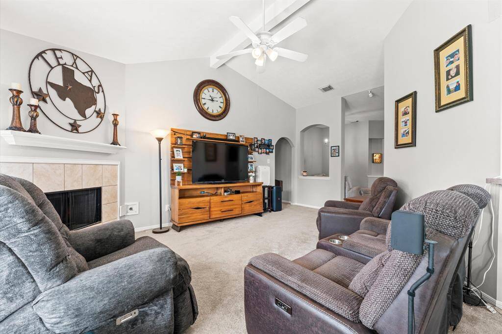 Cozy living room with plush recliners, a fireplace, and a large TV. Vaulted ceiling with fan and tasteful decor create a warm, inviting atmosphere. Perfect for relaxing and entertaining. (furniture and TV not included)