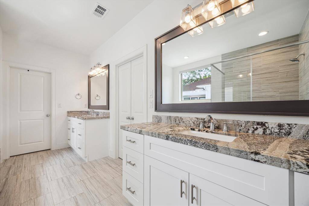 French Doors invite you into the Primary Bathroom that features two vanities with granite countertops & ample storage. The 2nd Walk In Closet is located through the door straight ahead.