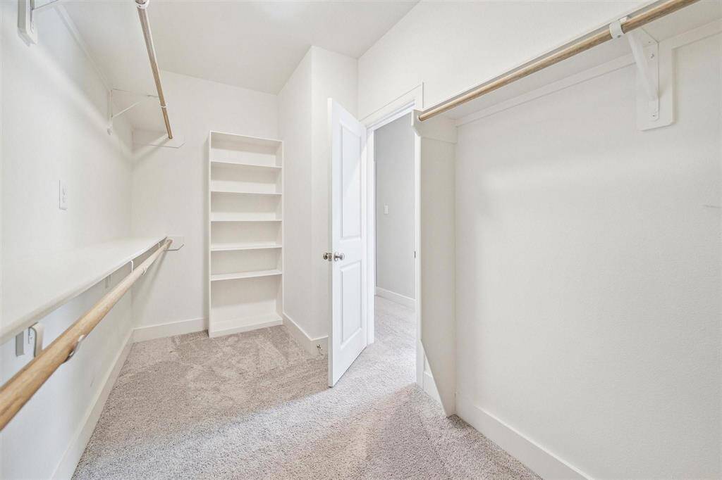 Walk in Closet #1 located across from the Primary Bathroom features tons of hanging space and custom shelving.