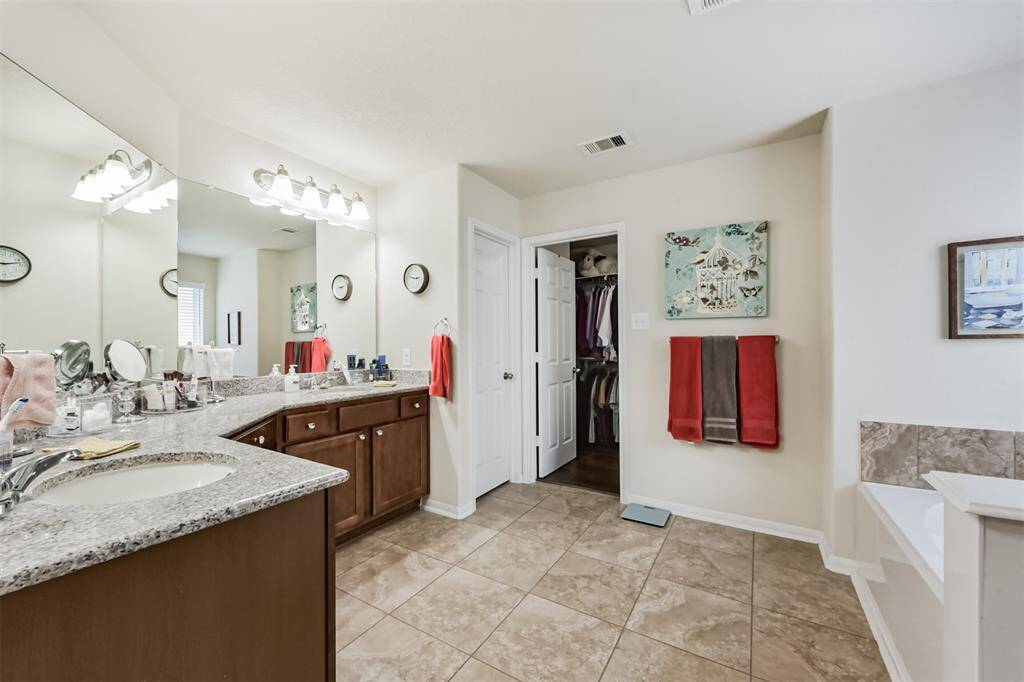The primary bathroom features dual sinks, a vanity area, soaking tub, separate shower, water closet, and walk-in closet.
