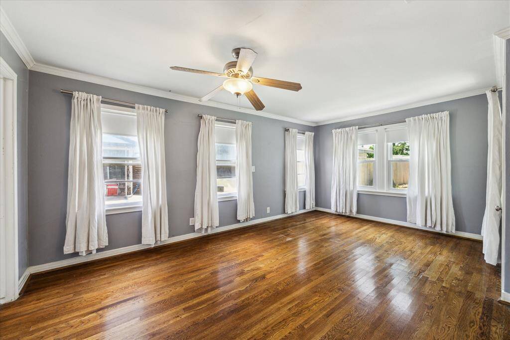 Primary bedroom with hardwood floors and multiple windows looking into the back yard