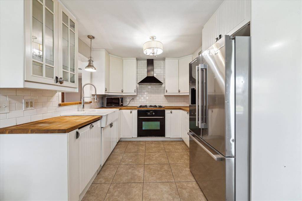 Light, bright kitchen with butcher block countertops, farmhouse sink and tons of storage space