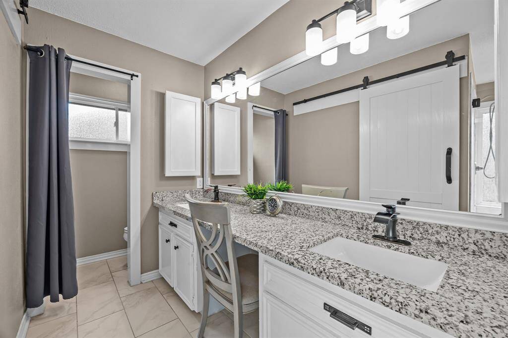Fantastic primary bathroom with double sinks, vanity area, and tile flooring.
