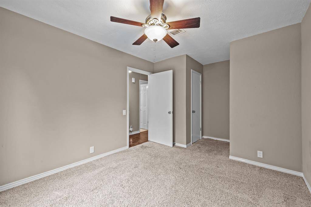 Spacious second bedroom with plush carpet, neutral walls, and a ceiling fan for comfort.
