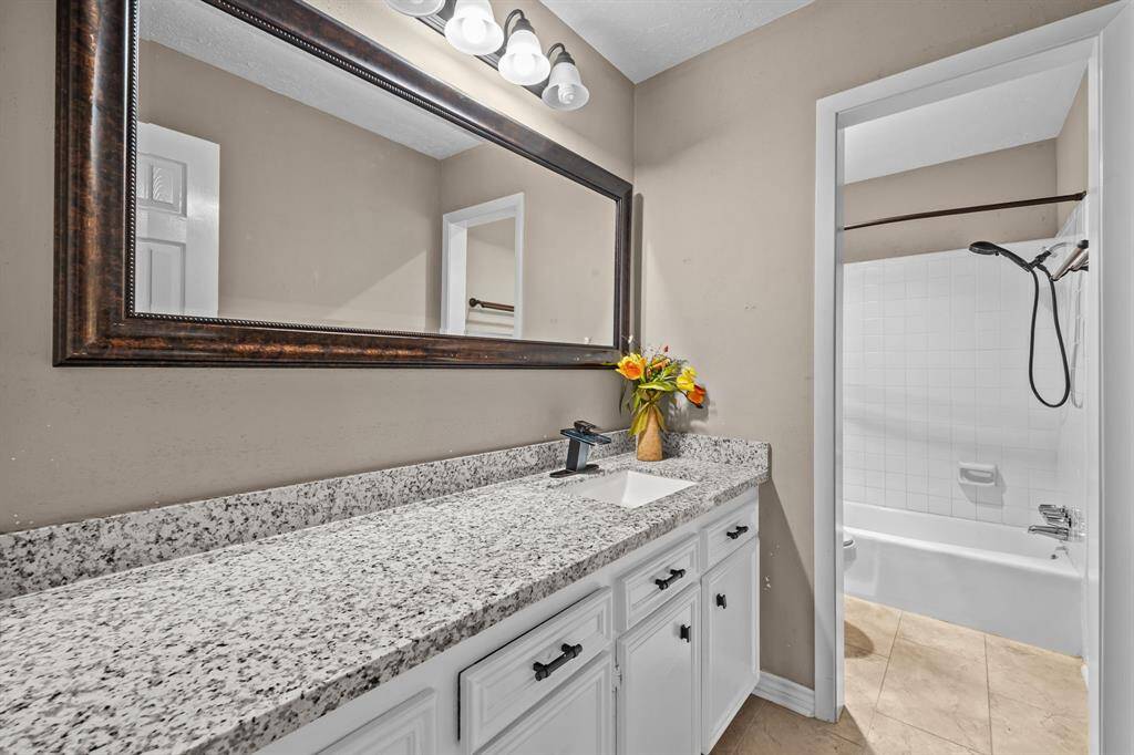 Hall bathroom with tons of cabinet space, tile flooring, and a tub/shower combo.