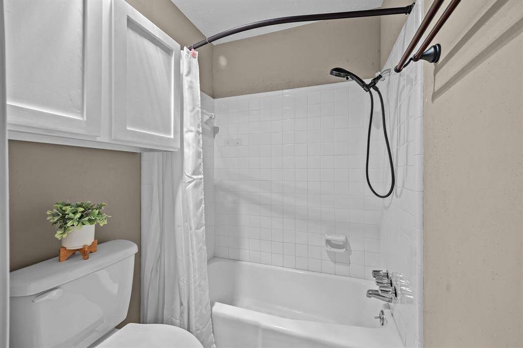 Hall bathroom with a tub/shower combo and built in storage.