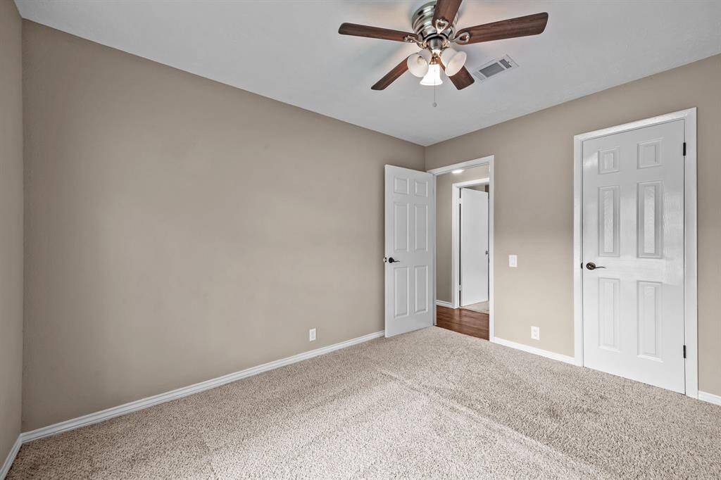 Cozy third bedroom with soft carpeting and a ceiling fan for comfort.
