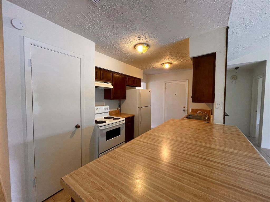 Another view of the ktichen featuring a pantry, electric range and white refrigerator.