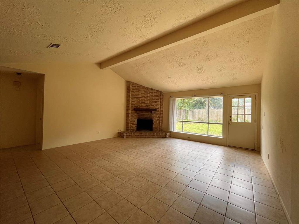 Large Living Room with fireplace and large window overlooking the backyard.