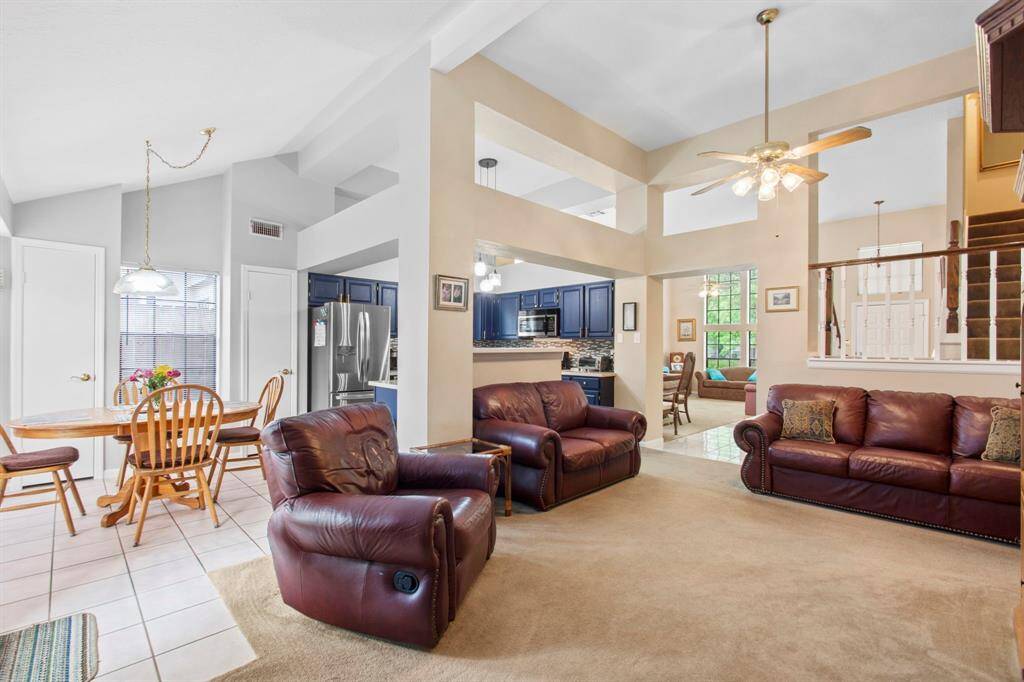 This spacious living area features high ceilings and an open layout connecting the kitchen, dining, and seating spaces. It provides ample natural light, perfect for family gatherings and entertaining.