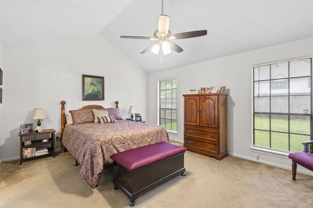 Spacious primary bedroom with vaulted ceilings, abundant natural light, and a serene view of the backyard.