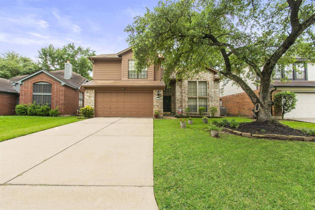 This charming two-story home features a brick facade with a two-car garage. The property is complemented by a well-maintained front lawn, mature trees, and a neat driveway, offering great curb appeal.